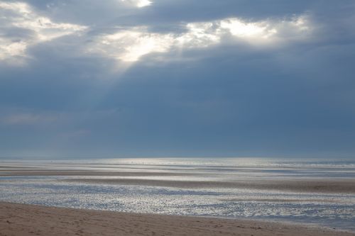 Free Peaceful seascape with sunbeams piercing clouds at Cabourg Beach, France. Stock Photo