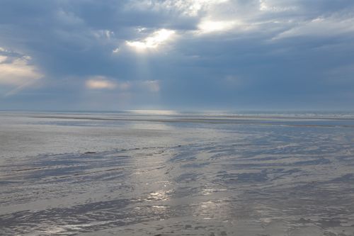 Free Moody seascape with overcast sky and sunlight breaking through clouds in Cabourg, France. Stock Photo