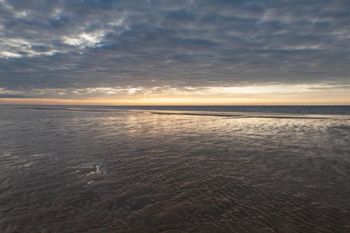 Free Tranquil sunset over the beach in Cabourg, Normandy, France. Serene ocean view under a cloudy sky. Stock Photo