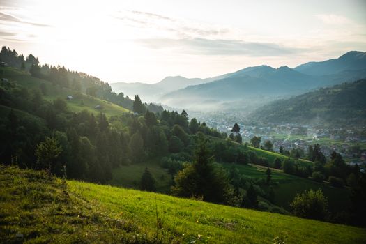 Peaceful morning view of a mountain village at sunrise, surrounded by green hills and mist.. pexels, peaceful, morning