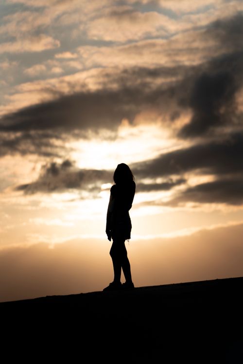 Free A woman silhouetted against a dramatic sunset sky in Hat Head, Australia. Stock Photo