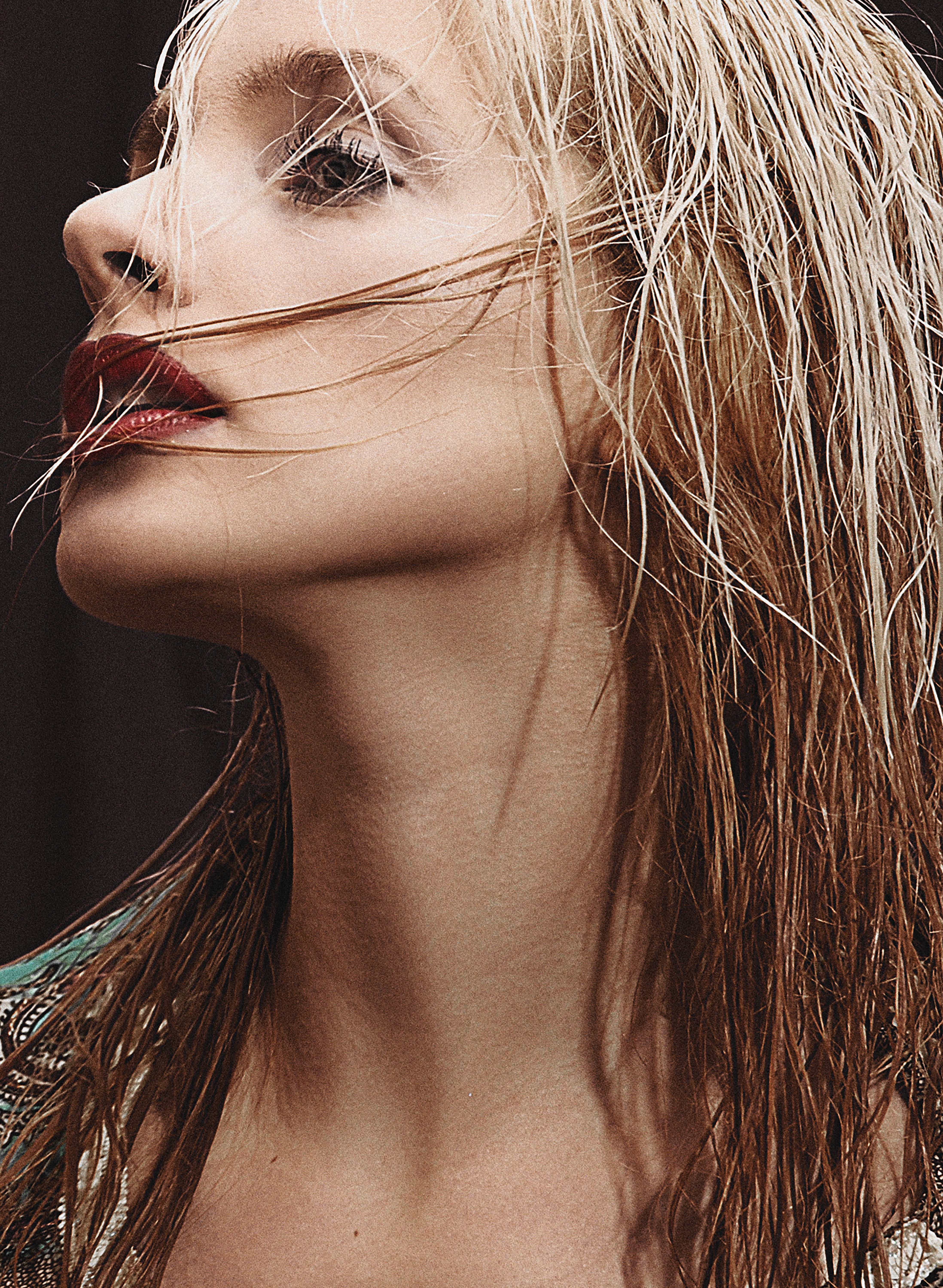 Close-up portrait of a fashionable blonde woman with red lipstick and tousled hair.