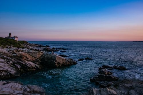 Free Beautiful sunset over the ocean with Beavertail Lighthouse and rocky shoreline in Jamestown, RI. Stock Photo