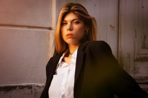 Free Stylish young woman in blazer posing confidently in soft outdoor light. Stock Photo