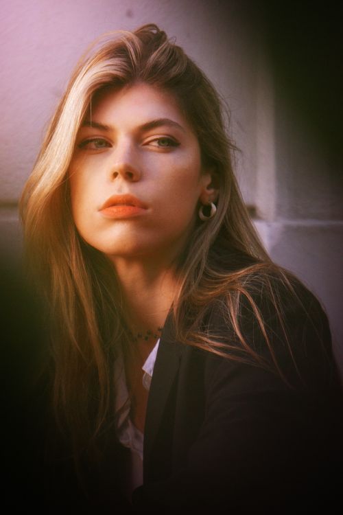 Free An elegant woman gazing thoughtfully to the side in a softly lit indoor setting. Stock Photo