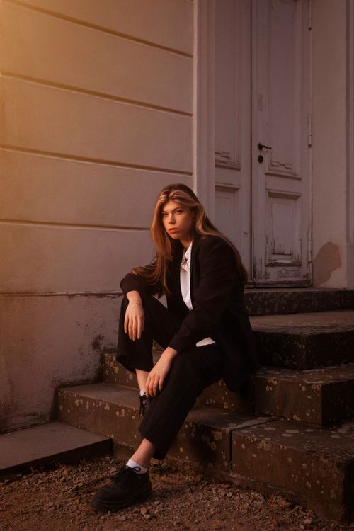 Free Fashionable woman in a blazer sitting on stone steps, capturing a contemplative mood. Stock Photo