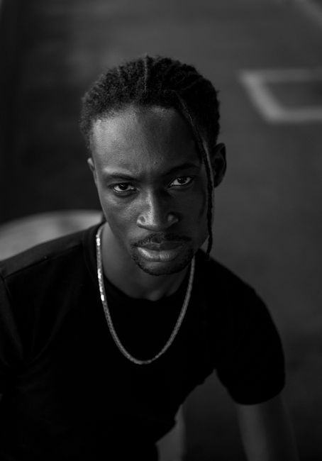 Expressive black and white portrait of a man with dreadlocks and necklace in Belo Horizonte, Brazil.