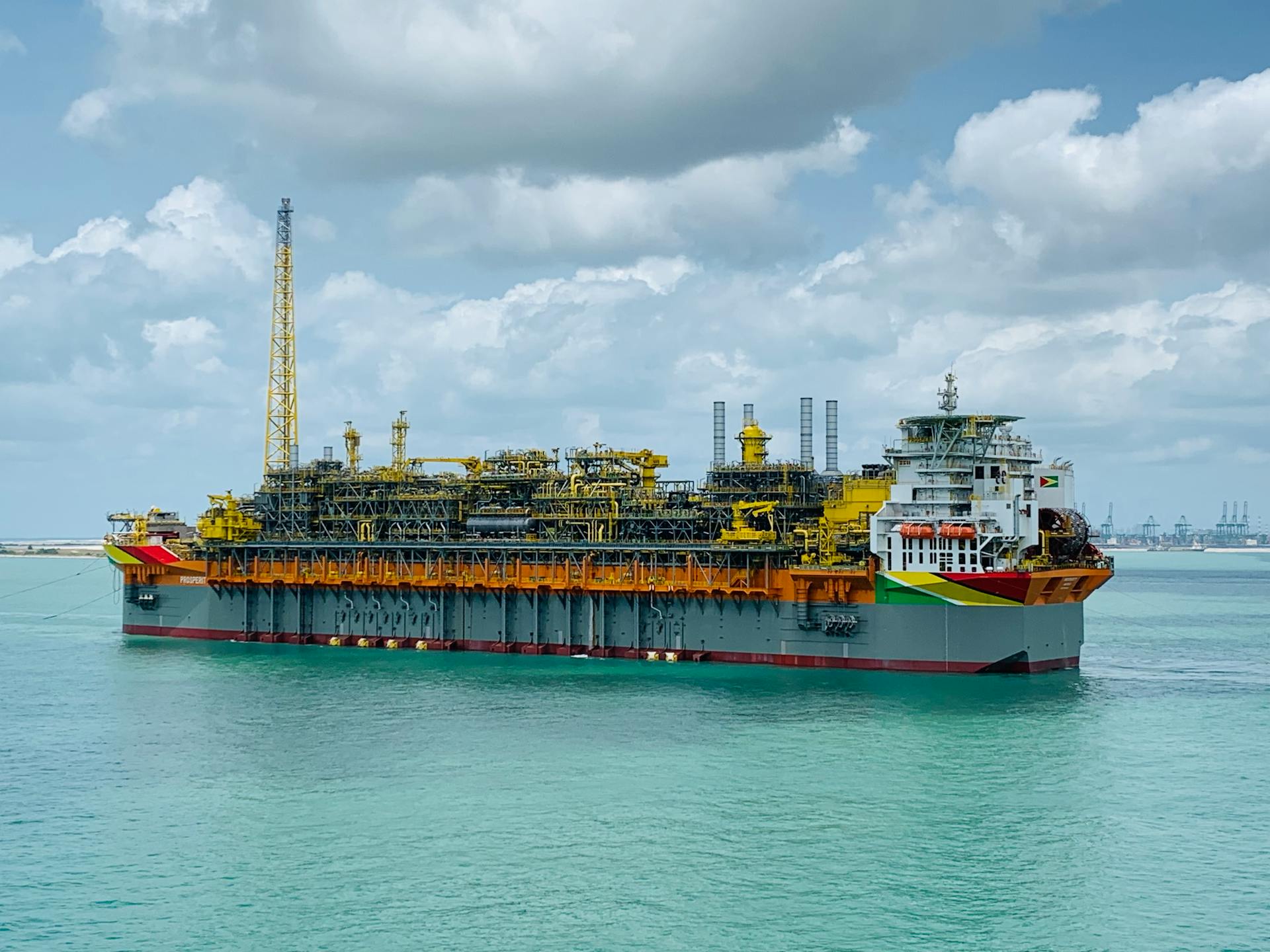 An oil rig ship anchored offshore under a cloudy sky, showcasing massive infrastructure in open waters.