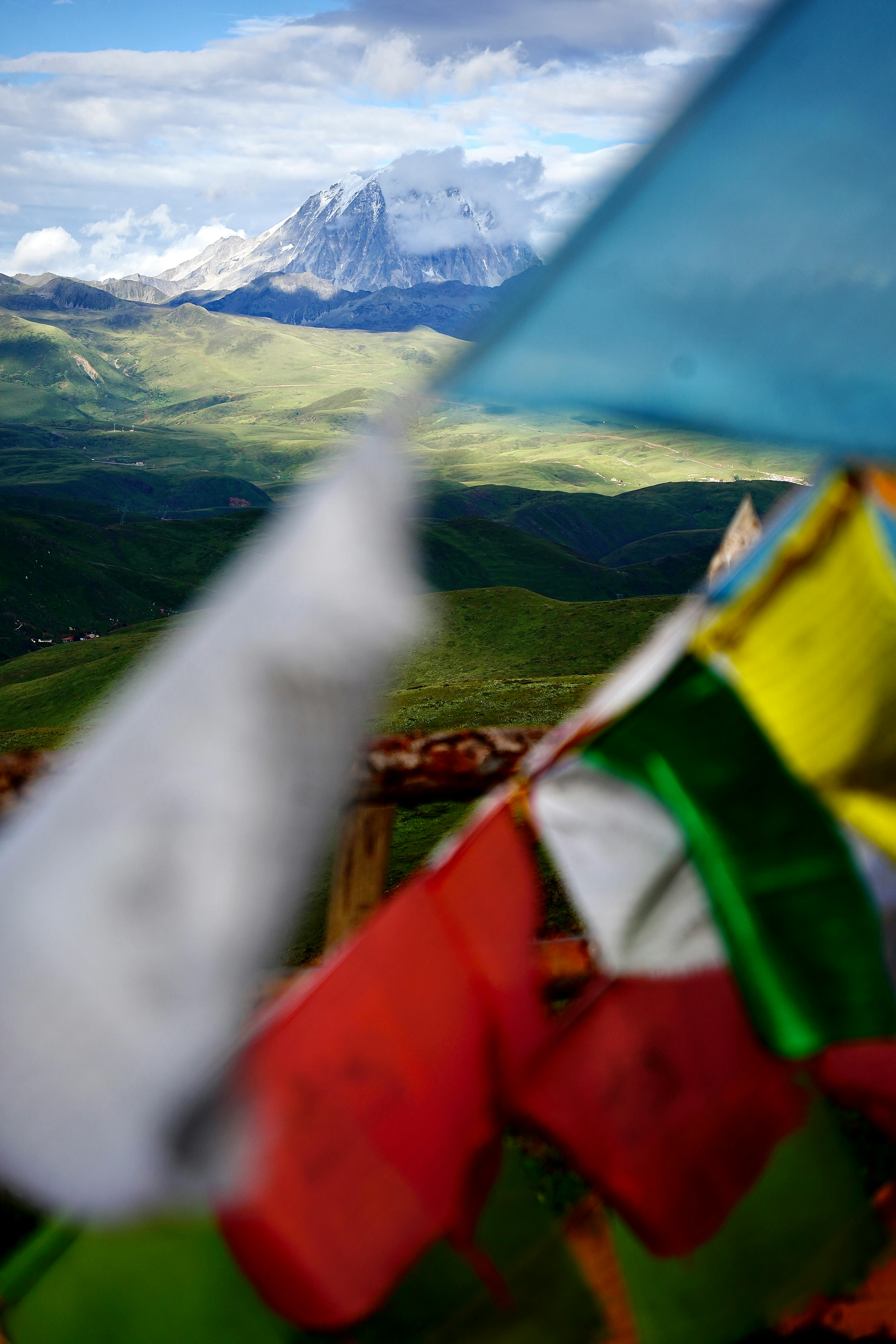 Vibrant Tibetan prayer flags gently fluttering with a stunning mountain backdrop in Sichuan, China.