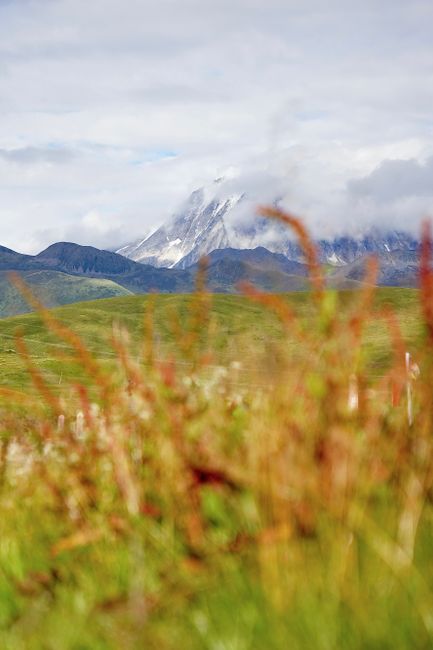 Scenic landscape with mountains, clouds, and fields in a vibrant natural setting.