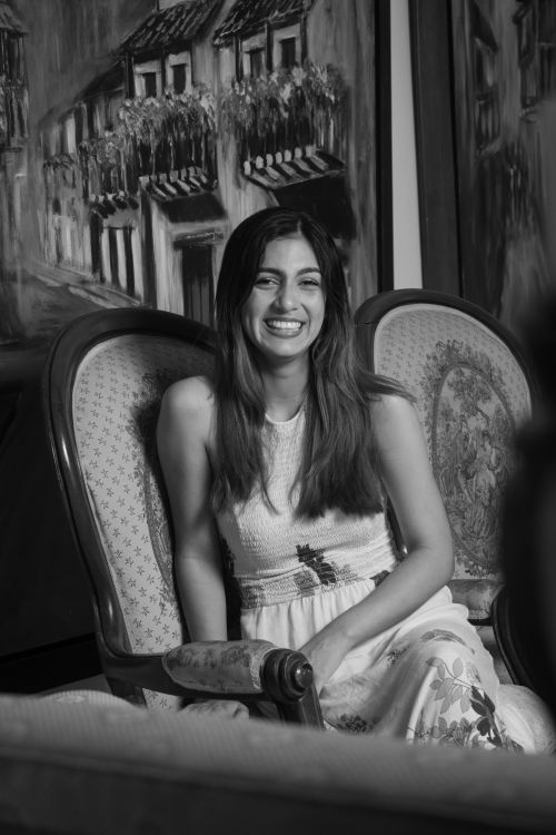 Free A woman smiling while sitting in a vintage armchair, surrounded by art pieces. Stock Photo