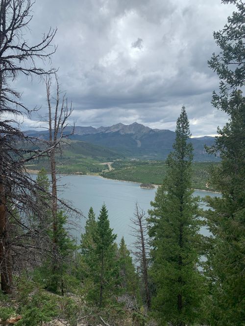 Free Breathtaking view of a mountain lake surrounded by forest and mountains under cloudy skies. Stock Photo