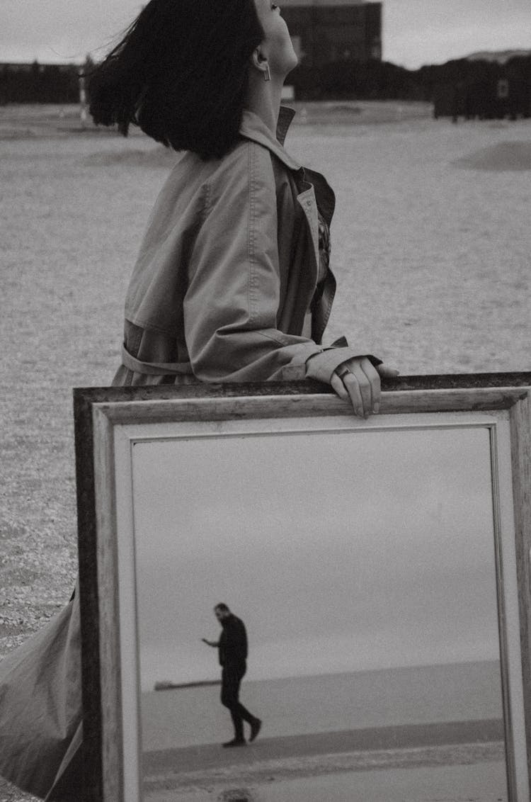 Woman Walking On The Beach With A Mirror