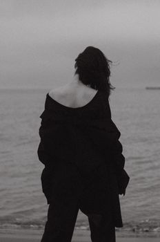 A person stands on a beach in Baku, captured in a moody black and white style.