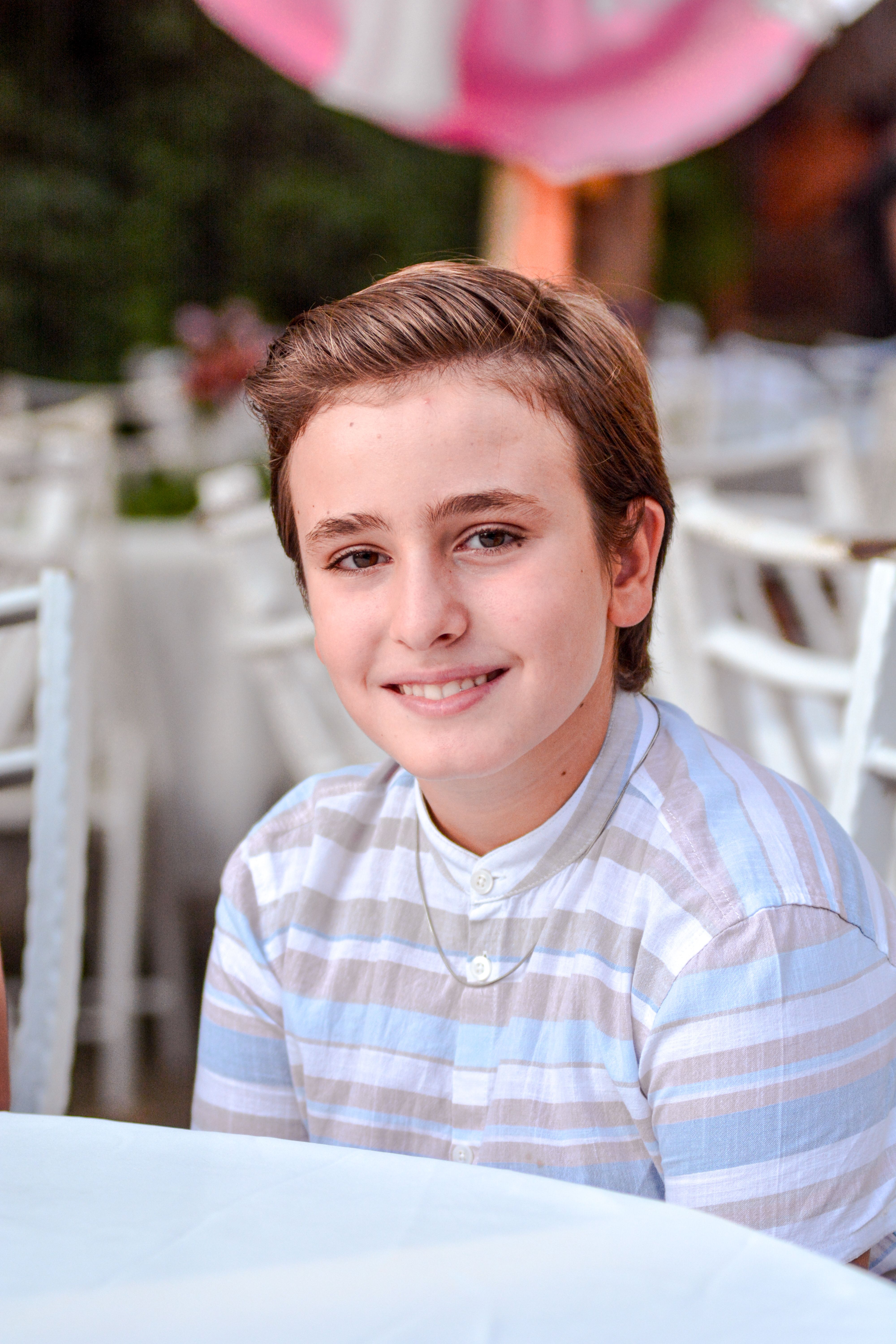 A teenage boy with short brown hair smiling at an outdoor event in Salihli, Türkiye.