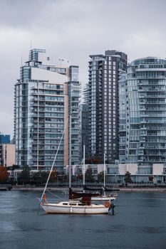A serene view of a sailboat in front of Vancouver's urban skyline, showcasing modern residential towers.