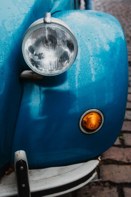 Detailed front view of a classic blue Citroen 2CV showing the headlight and fender.