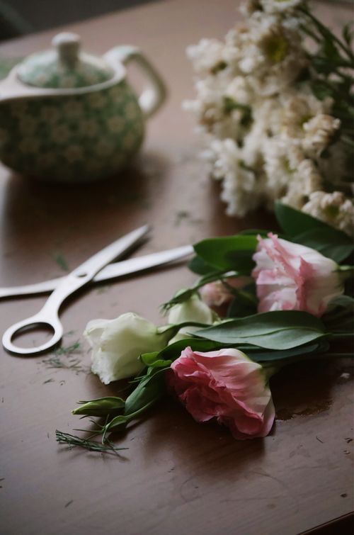 Free Delicate floral arrangement on a wooden table with scissors and a teapot. Stock Photo