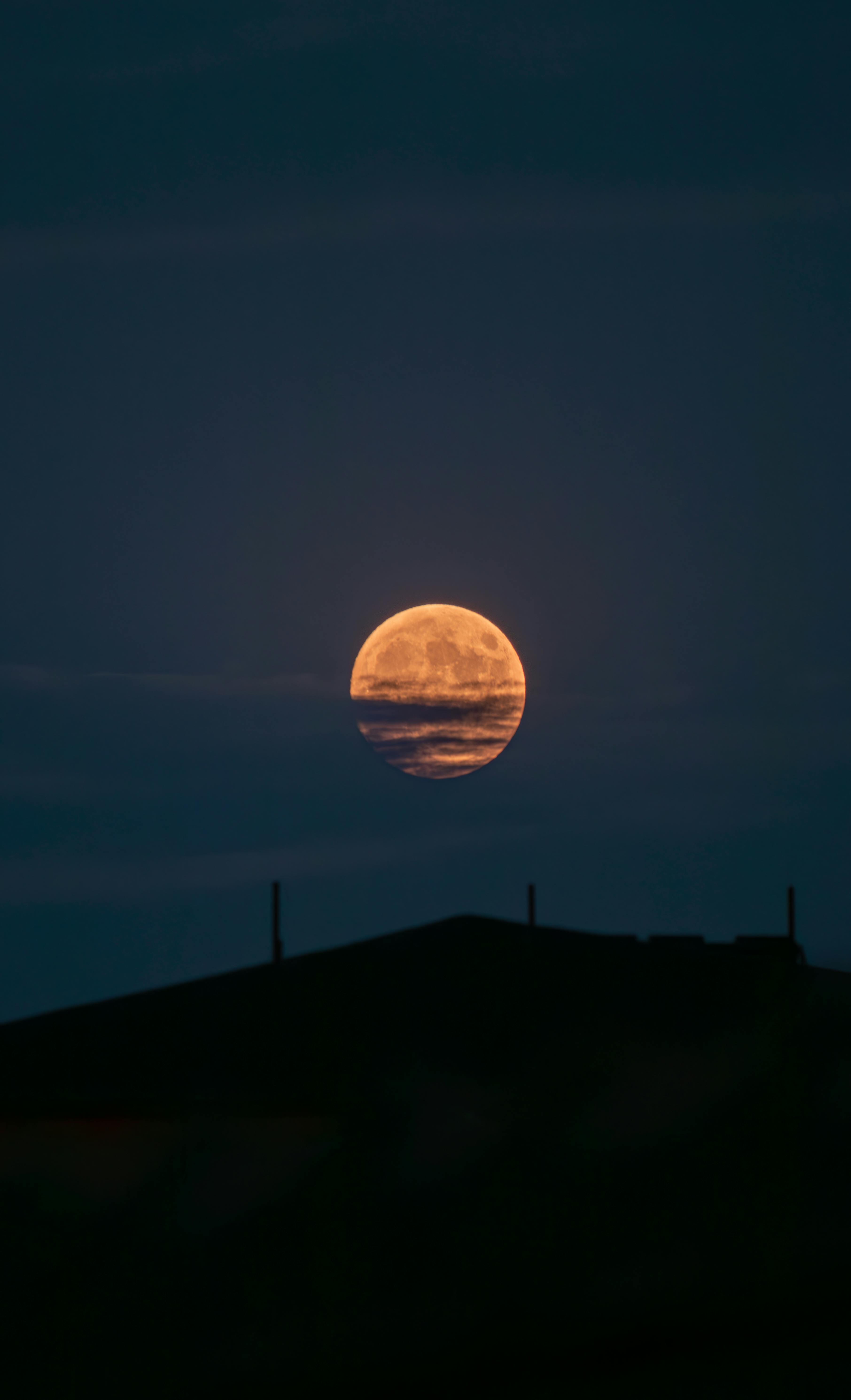 Dramatic full moon rising over a dark silhouette of a hill in Merzifon, Amasya, Türkiye.