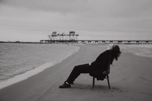 Free A woman in black attire sits on the beach chair near the sea in Bakı, capturing solitude. Stock Photo
