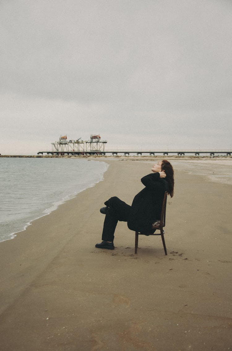 Model In Coat And Pants At Beach On Gloomy Day