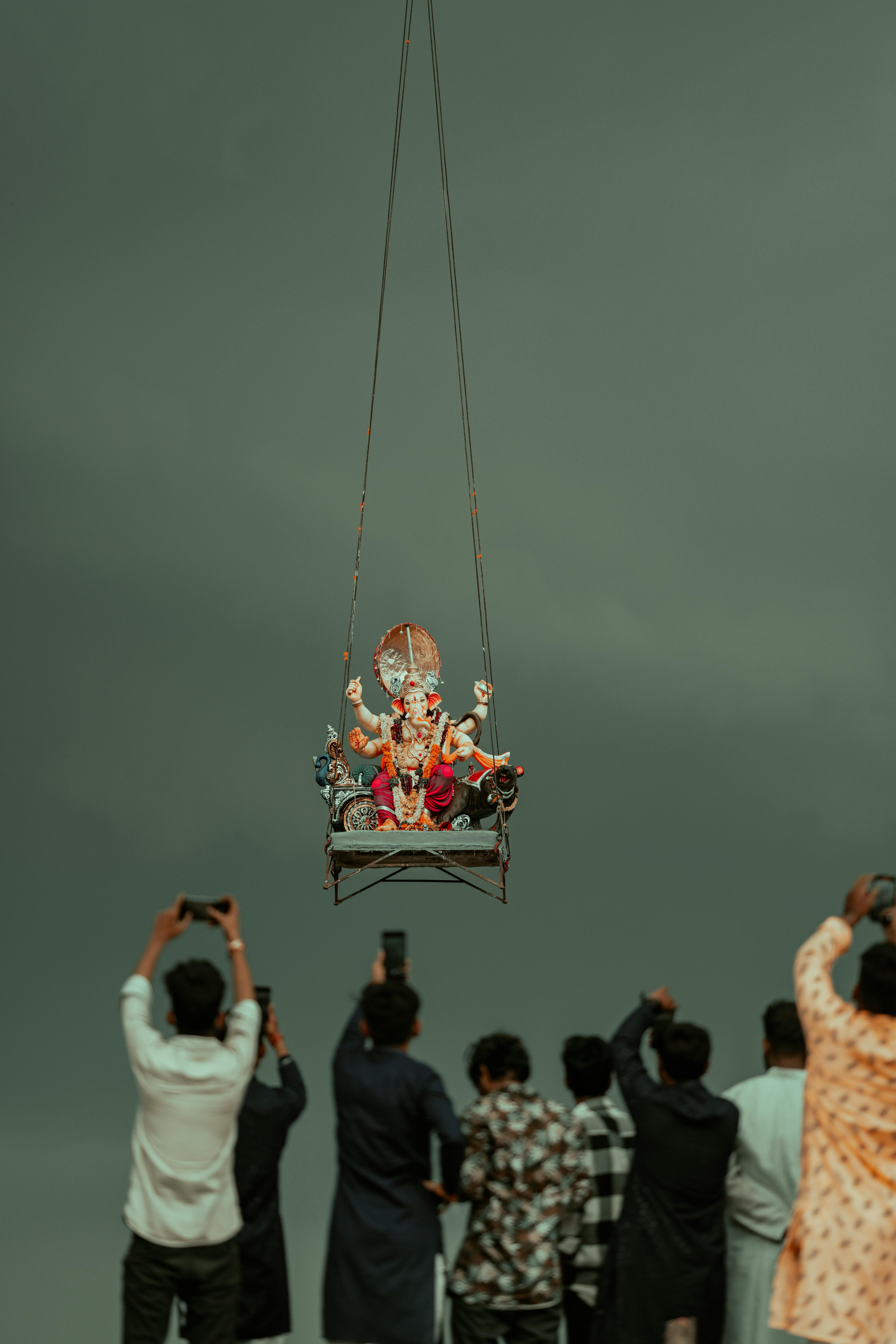 Men Taking Photos of a Ganesha Deity Statue Raised on Ropes During the Hindu Festival Ganesh