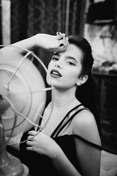 一幅优雅的黑白肖像，描绘了一位女士手持古董扇子在室内的留影