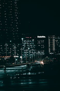 A vibrant night cityscape featuring tall skyscrapers and illuminated streets, showcasing urban life.