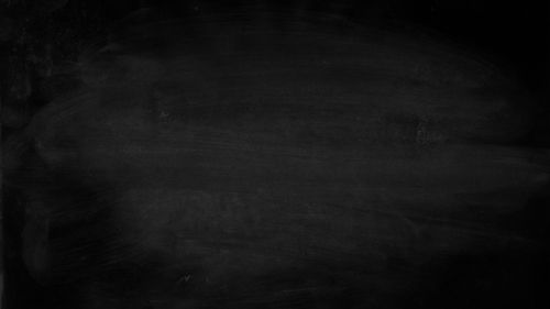 Free A simple black chalkboard displaying erased chalk marks. Perfect for educational or presentation themes. Stock Photo