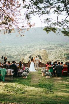 An outdoor wedding ceremony in Tiradentes, Brazil with newlyweds and guests amid lush countryside.
