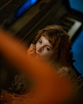 一位红发体贴的女人若有所思地坐在三角钢琴旁