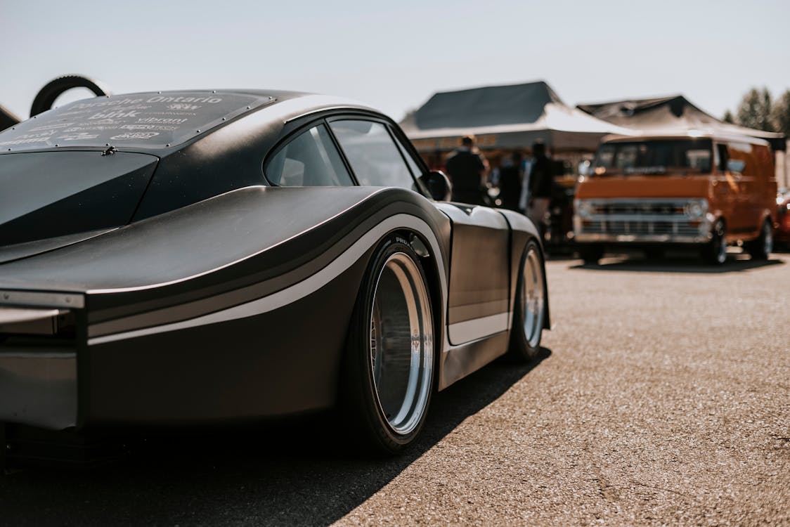 A Modern Sports Car and a Vintage Van on a Parking Lot at a Car Show 