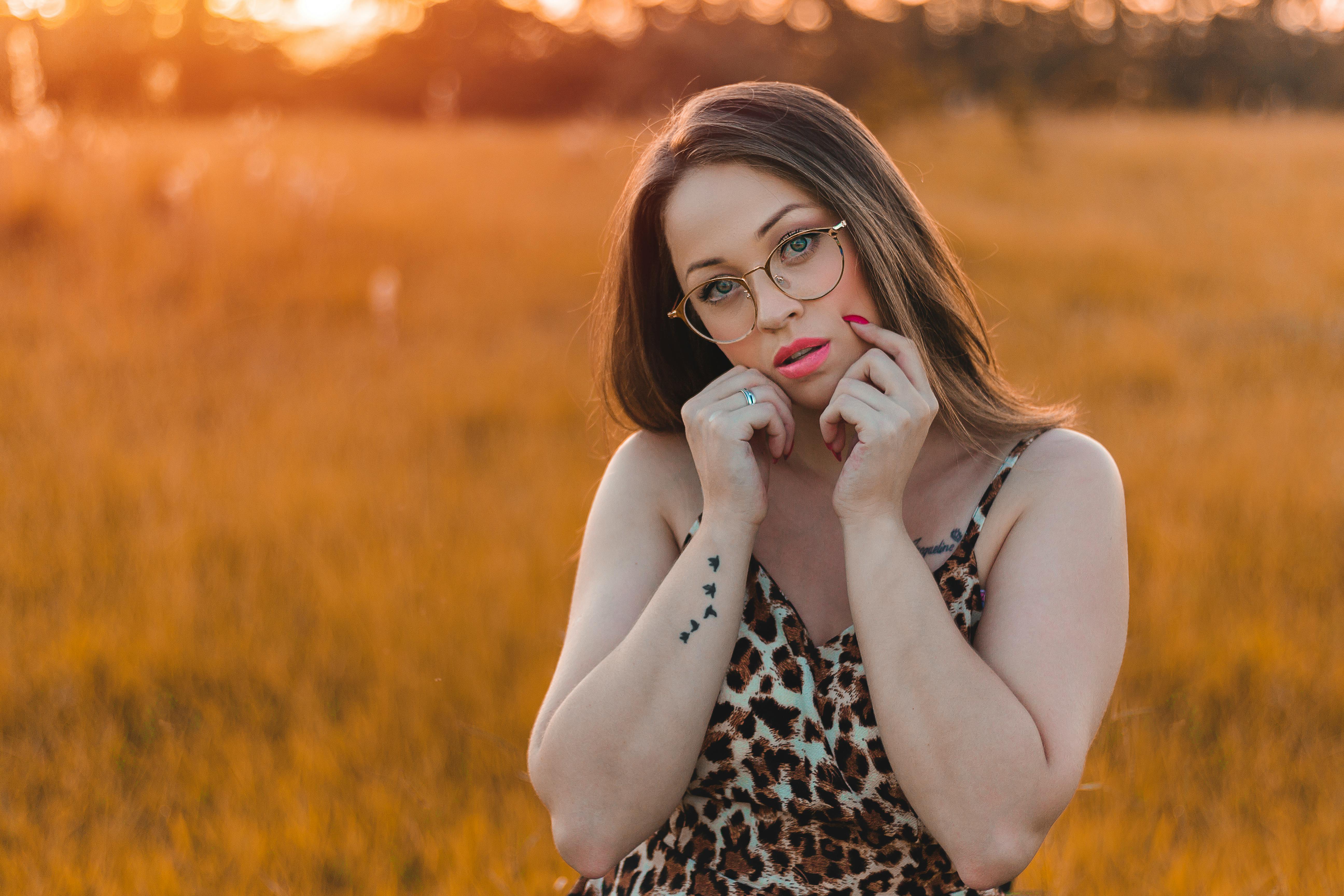 日落时分，一名戴眼镜、有纹身的女子穿着豹纹连衣裙摆着姿势