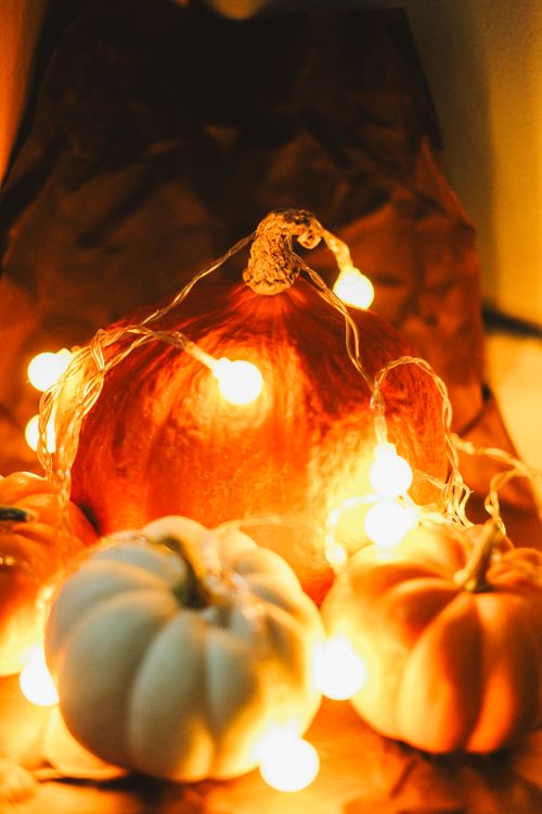 Free Close-up of pumpkins adorned with glowing string lights, perfect for cozy autumn aesthetics. Stock Photo