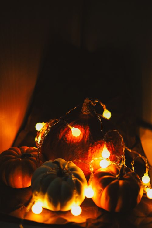 Free Festive Halloween scene featuring pumpkins and warm glowing lights creating a spooky atmosphere. Stock Photo