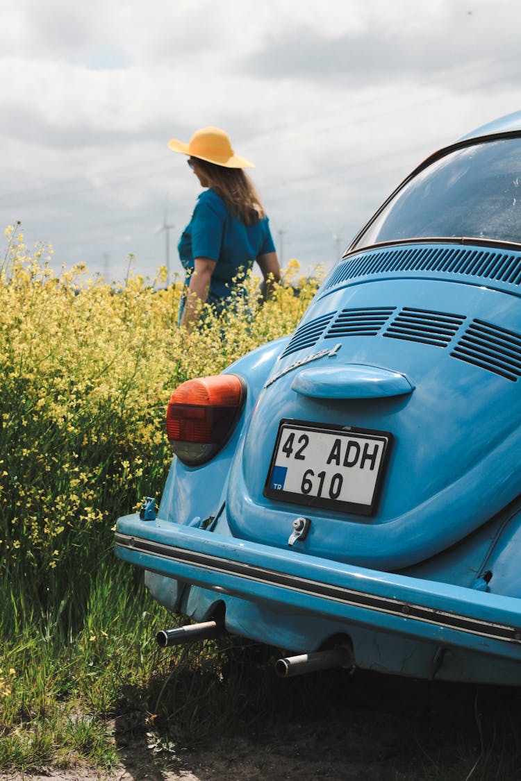 A Woman Walking On A Field Near A Vintage Car