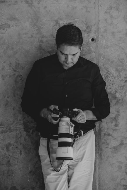 A professional photographer analyzes his camera equipment in a black and white setting.