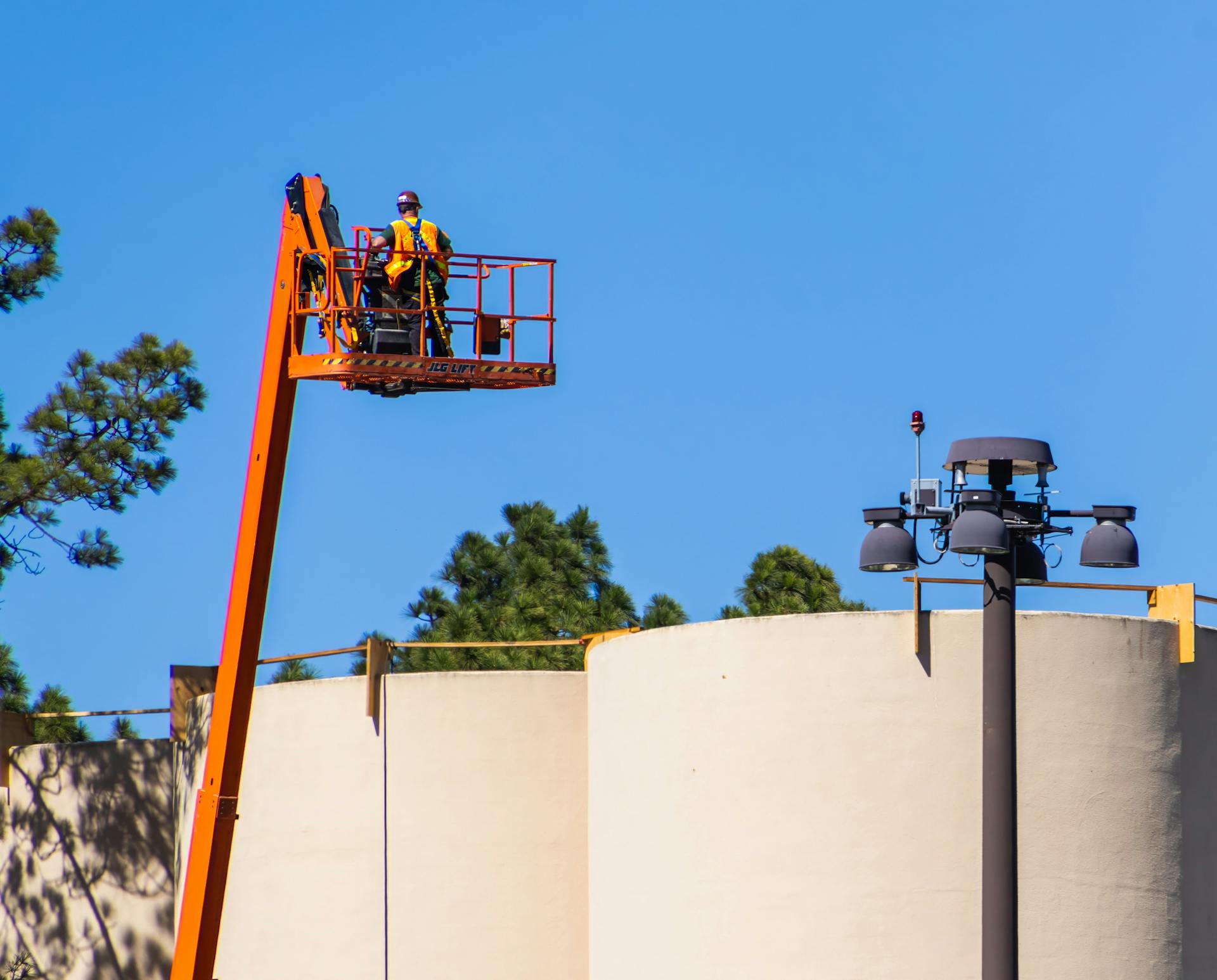 Construction worker on an elevated boom lift at a construction site, bright day.