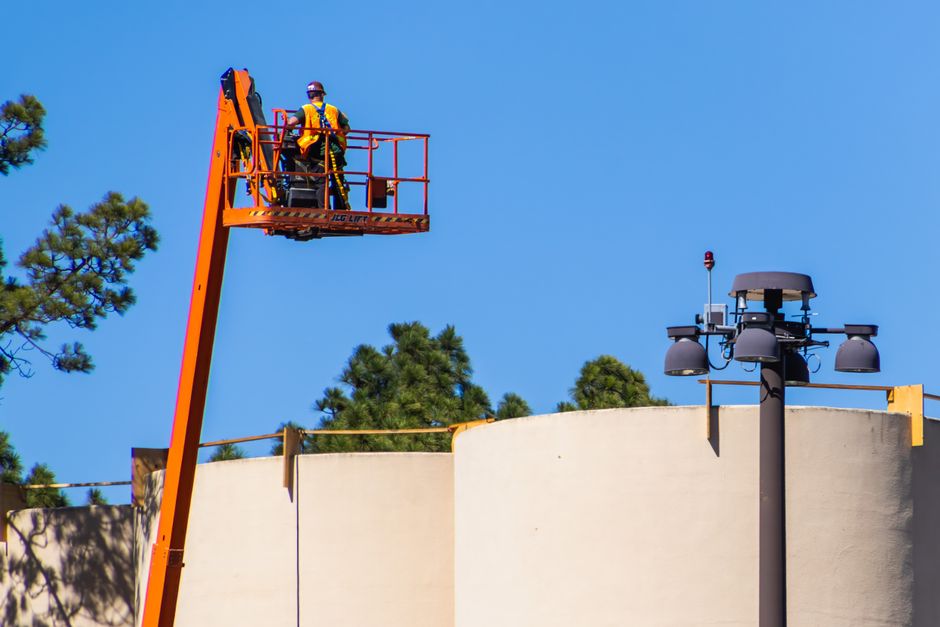 Worker on a boom lift platform above tree canopy — aerial access equipment is a major driver of tree trimming service cost in Surrey BC