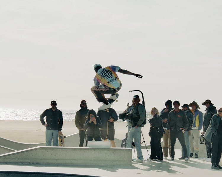 Group Of People Watching And Photographing A Skateboarder At A Skatepark 