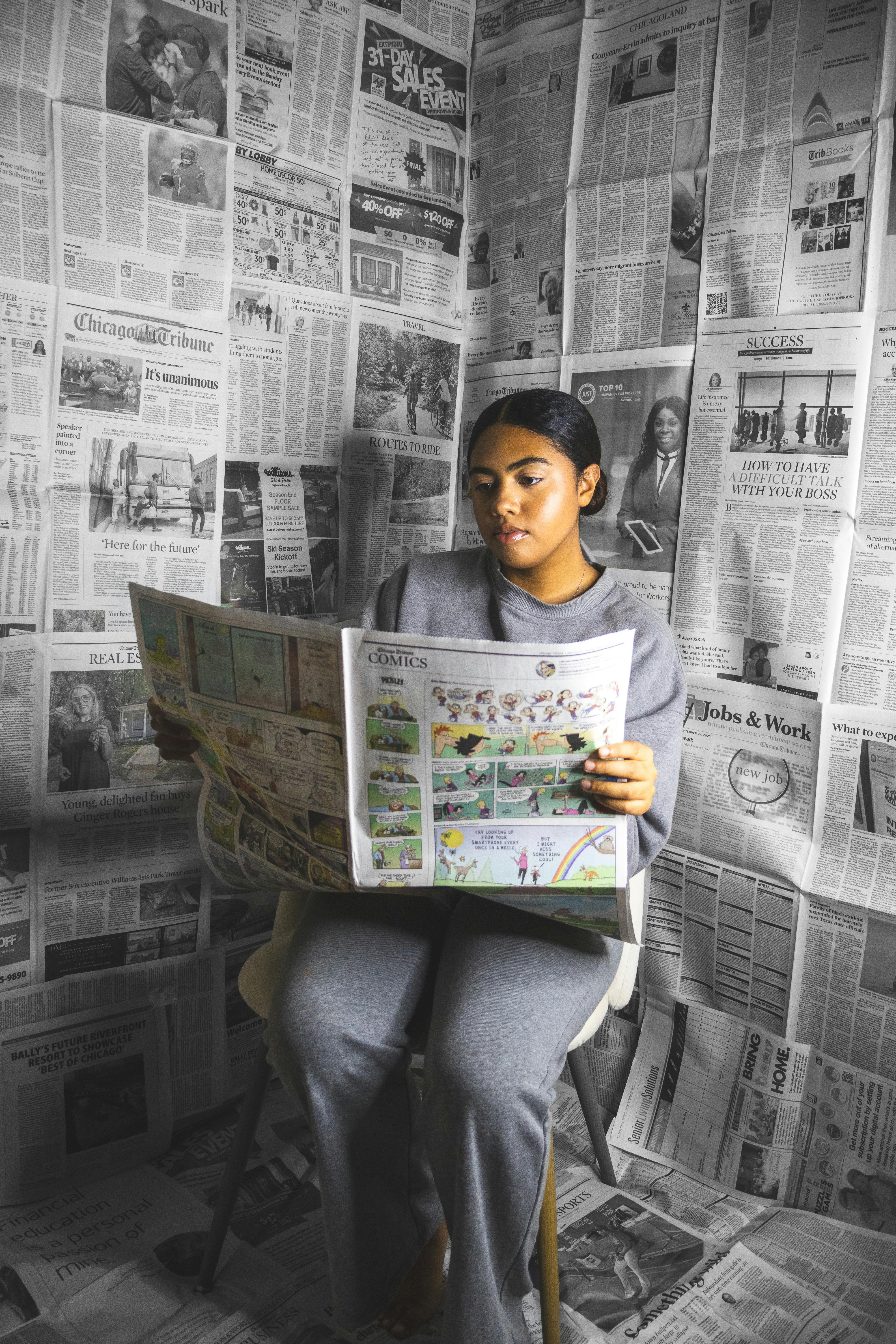 woman sitting among newspapers