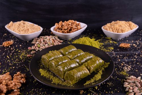 Free Delicious close-up of baklava rolls garnished with pistachios and walnuts on a rustic plate. Stock Photo