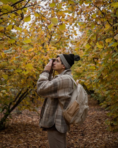 Tourist with a Camera and a Beige Backpack in an Autumn Park