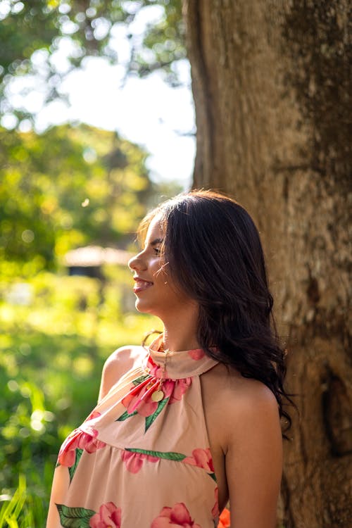 Happy Young Woman in Dress Posing by Tree