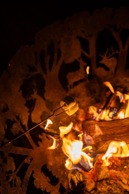 Free Close-up of marshmallow roasting over a decorative fire pit, evoking warm campfire vibes. Stock Photo