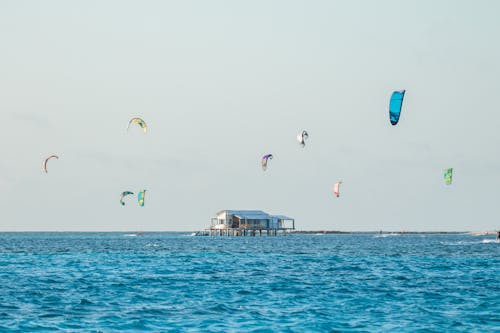 Kiteboarders Swimming Near Stilt House in the Sea