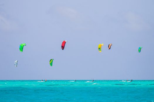 Kiteboarders enjoying a bright summer day on the vibrant turquoise sea with colorful kites.