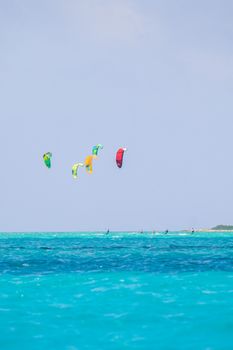 Colorful kiteboarders enjoy the ocean under a clear blue sky, capturing a perfect summer day at sea.