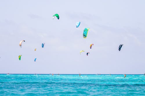 Colorful Power Kites of a Group of Kiteboarders Over the Turquoise Sea
