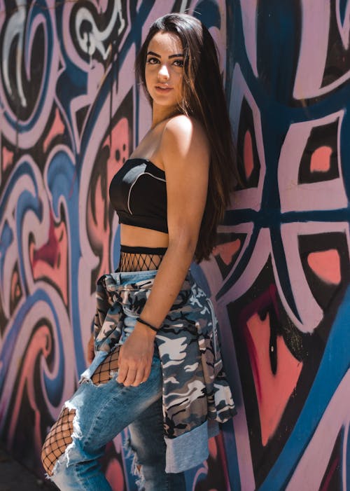 Free Woman Wearing Black Sports Bra Leaning on White and Blue Painted Wall Stock Photo